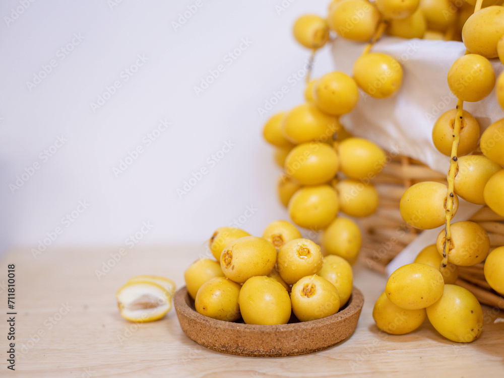 Close up and selective focus fresh dates fruits in wooden plate. Close up and selective focus fresh dates fruits in wooden plate.