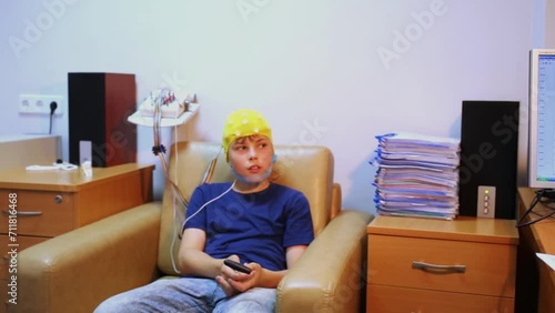 doctor looks at display with live charts, boy in special cap sits photo