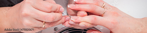 manicurist working on the nails of a female client, tidying up the manicure and putting the health of the nails in order, close-up photo