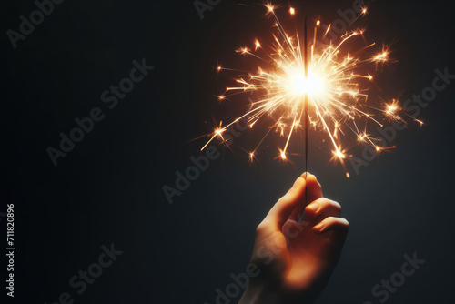 Beautifully burning sparkler on dark background. Space for text.