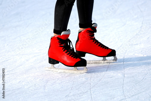 Winter skating rink. Red skates skate on the ice. Active family sport during the winter holidays and cold season.