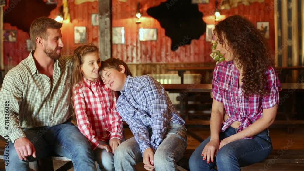 Family of four persons sits on a wooden bench in saloon