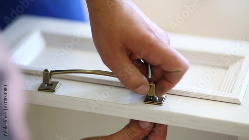 The man fastens the handle to the drawer, visible only hands photo
