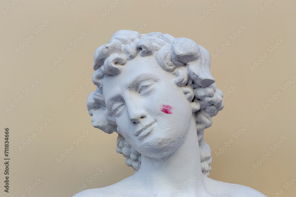 Head of a male garden sculpture with a lipstick kiss on his cheek