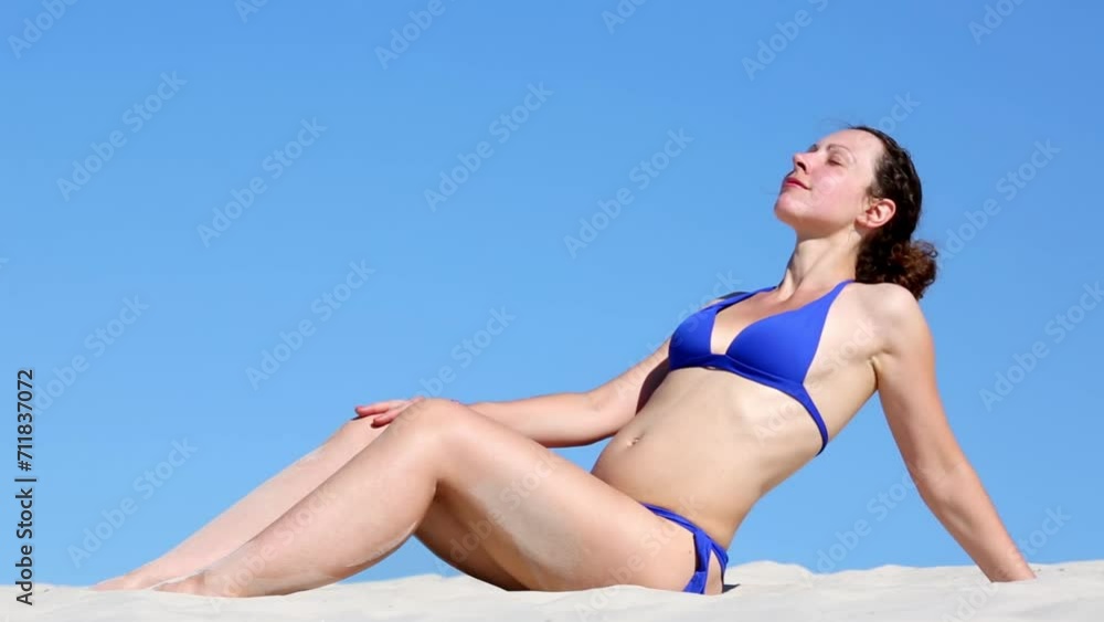 Beautiful girl enjoying the sunbathing and sorts out the sand Beautiful girl enjoying the sunbathing and sorts out the sand
