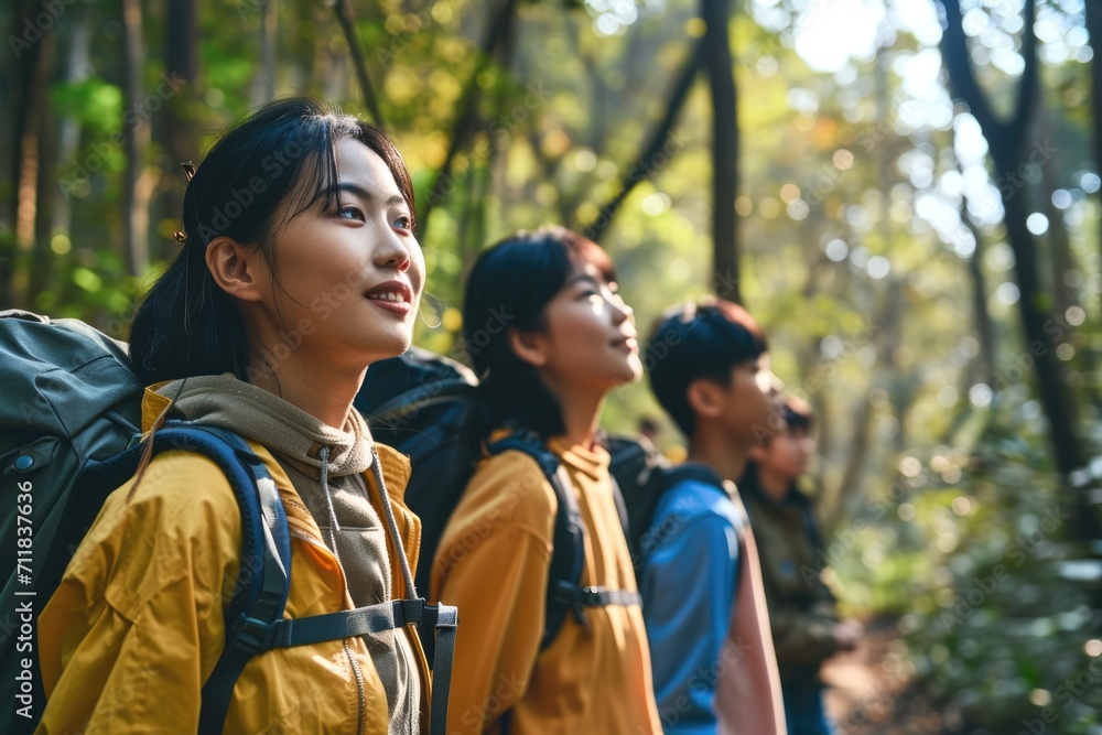 Young people, a company of Asians in the forest on a walk with backpacks looking at nature and trees. On a hike, laughing Young people, a company of Asians in the forest on a walk with backpacks looking at nature and trees. On a hike, laughing