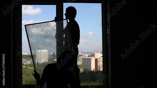 Silhouettes of workers who dismantle old window frame 
