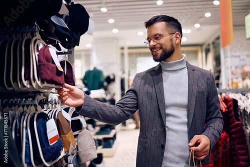 Young happy man buying knit hat in clothing store. photo