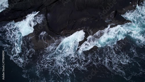 Top-down aerial shot of cold arctic ocean waves hitting rocky shoreline, no movement