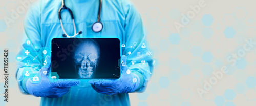 The doctor holds a tablet and examines a postero-anterior (PA) x-ray of paranasal sinuses. Doctor isolated on white background observes and analyzes the frontal and ethmoid sinuses. photo