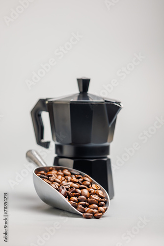 Roasted coffee beans in scoop on gray background.