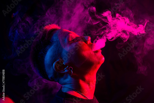 Portrait asian woman with shaved temples smokes vape in neon light.