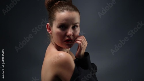 Pretty woman poses in jacket dressed backwards in black studio photo