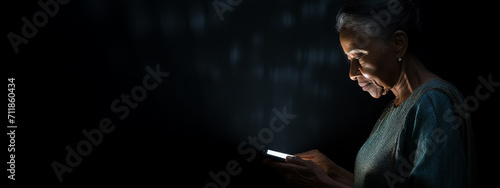 Old lady with the glasses looking at her mobile phone with dark background photo