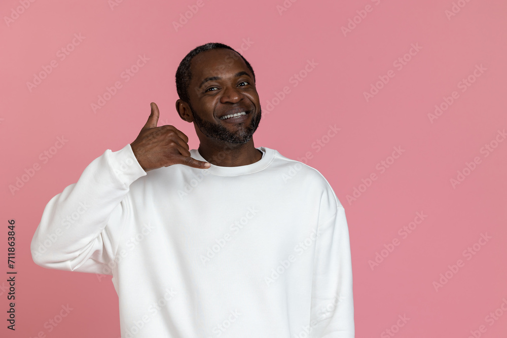 Handsome black man wearing white sweatshirt showing call me gesture Handsome black man wearing white sweatshirt showing call me gesture