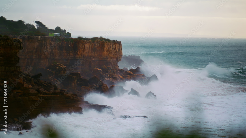 Stormy ocean breaking cliffs in slow motion. Powerful waves crashing wild rocky
