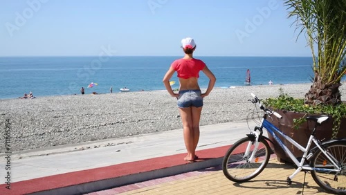 Back of woman in shorts looking at stony beach at summer photo