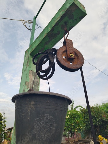 And old rusty pulley with worn rope made of rubber which people use to take water from well in village photo