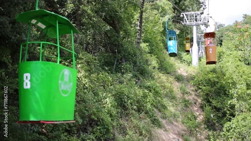 Colored funicular open wagons move through green trees at summer photo