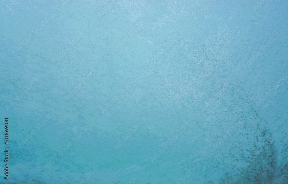 Eisbedeckte Glasscheibe mit Muster vor blauem Himmel bei Frost und Schnee am Morgen im Winter