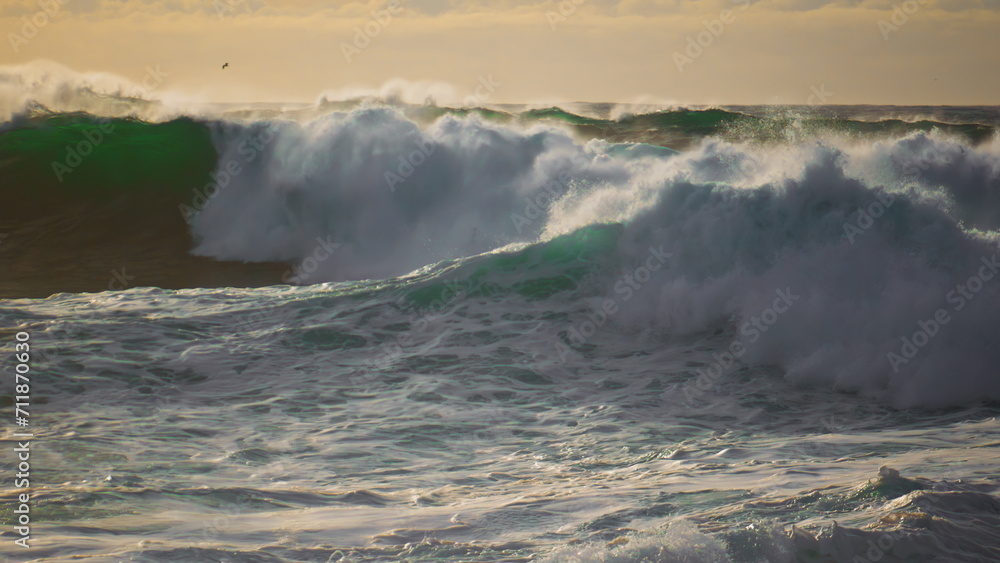 Dramatic stormy ocean waves splashing on sunny day. Extreme seashore landscape