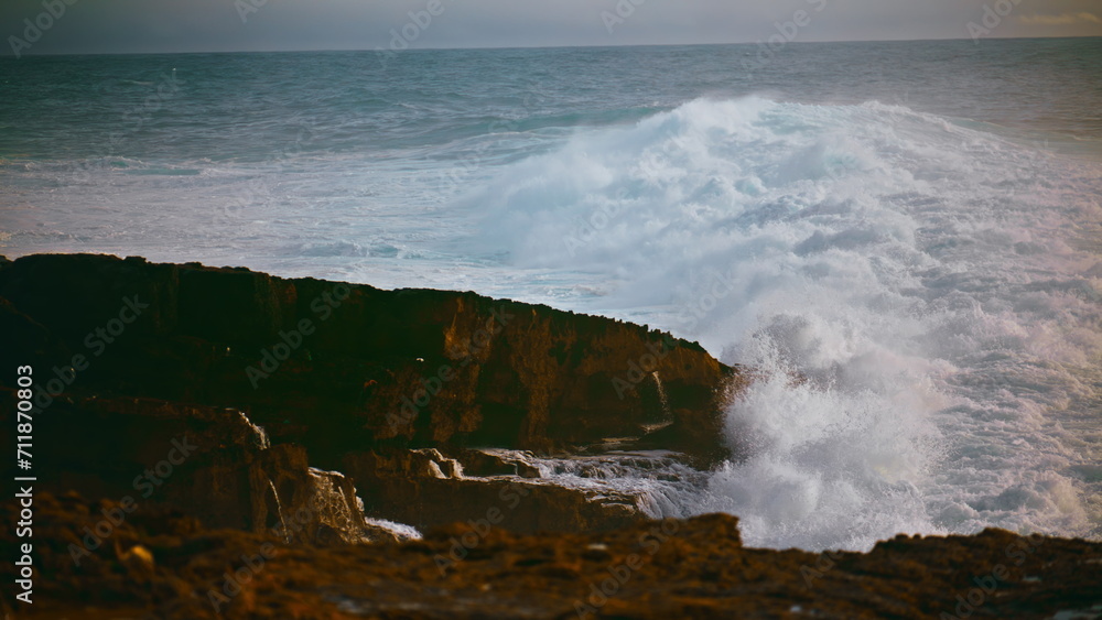 Coastal waves hitting stones on stormy day. Powerful ocean rolling hitting beach