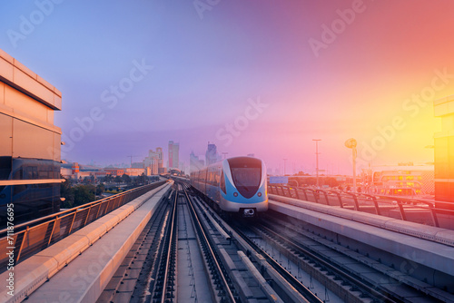 Dubai cityscape, modern metro railway with skyscrapers, sunset. Traffic train and building with urban skyline background of city UAE