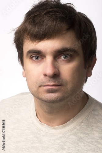 Portrait of a man with a neutral expression, wearing a light beige sweater. The subject is in focus with a plain white background, offering a professional and clean look, ideal for stock use