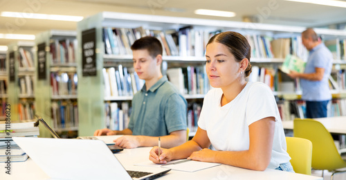 Female college student working on a project with a male student in the school library