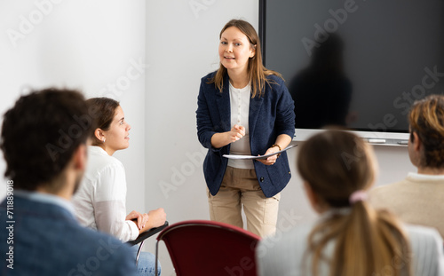 Experienced female teacher giving lecture to group of student photo