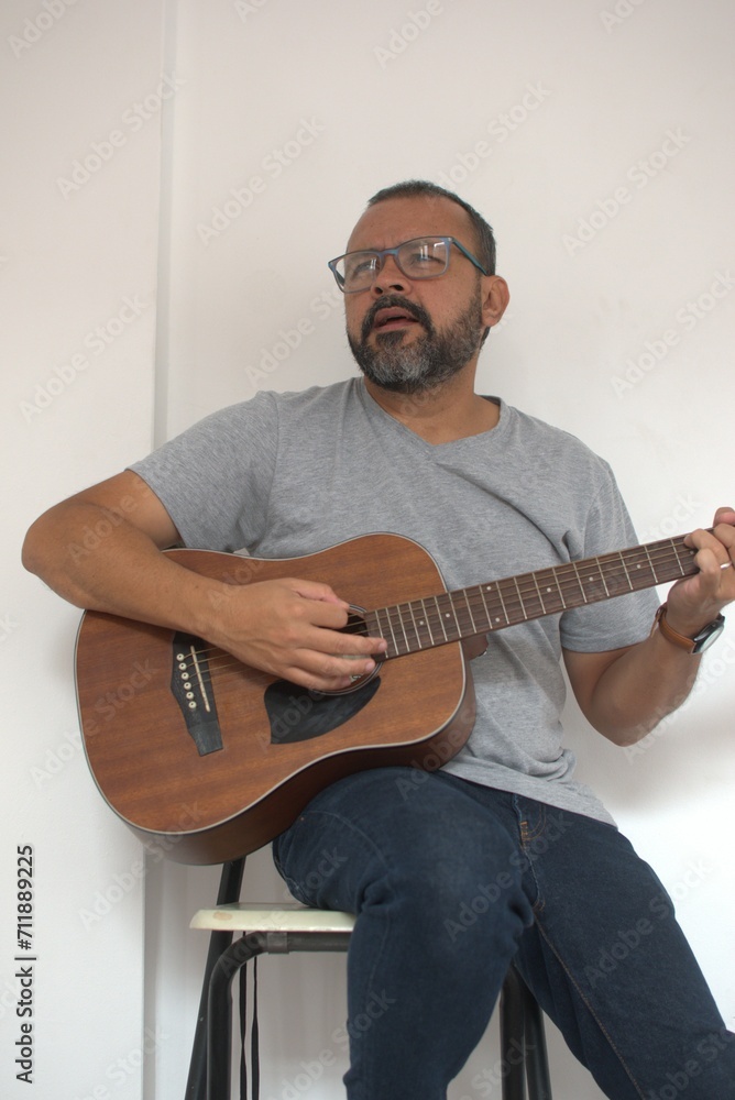 Aesthetic photo of an attractive, bearded hipster playing acoustic guitar outdoors at sunset.  acoustic guitar. Teacher.