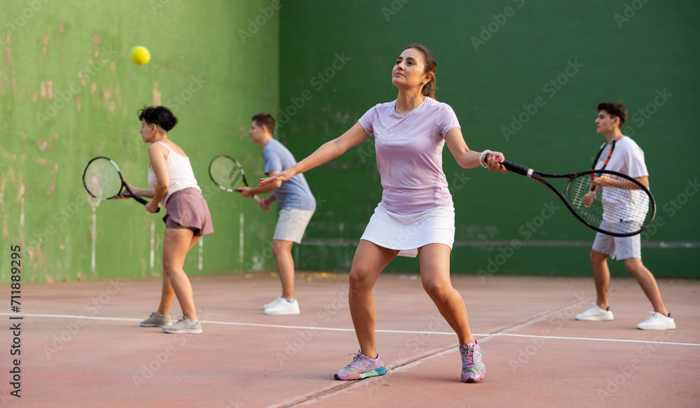 Sportive woman in shorts and t-shirt playing frontenis on outdoors court