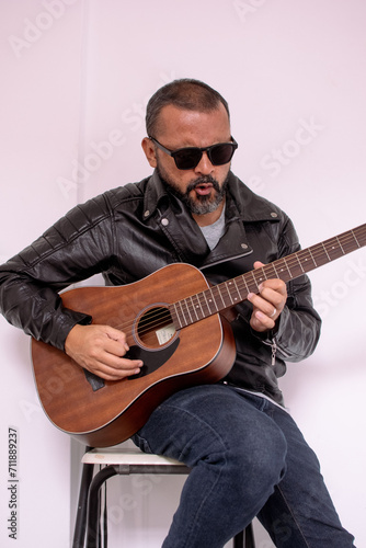 Aesthetic photo of an attractive, bearded hipster playing acoustic guitar outdoors at sunset. acoustic guitar. Teacher.