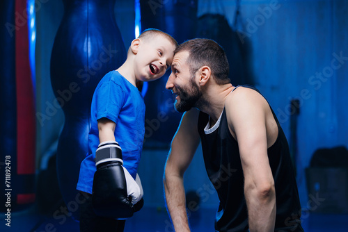 Boxing coach is training boy in gym. Young child men boxer practicing punches with trainer. Concept of family sports son and father © Parilov