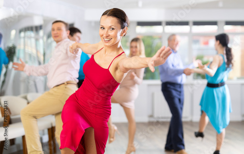 Positive adult pairs practicing vigorous jive movements in dance class