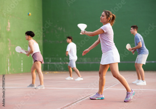 Young sporty woman performing basic strokes during paleta fronton group training © JackF
