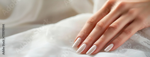 Fresh Manicure on Bridal Fingers. Woman s hand rest gently on her gown  showcasing the elegance of simplicity. Panorama with copy space.