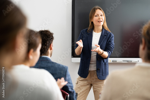 Fotografija Friendly female behind interactive board answering questions from listeners sitt