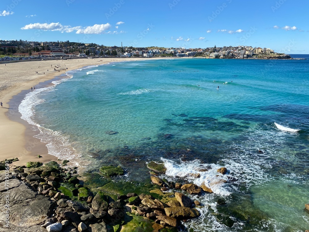 Bay and coastline close to the ocean. View of the city in the distance. Turquoise waves breaking on the rocky shore. Australia, Sydney landscape.