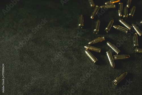 bullets for a combat pistol 9 mm gold color lies on a dark green or khaki background top view close-up