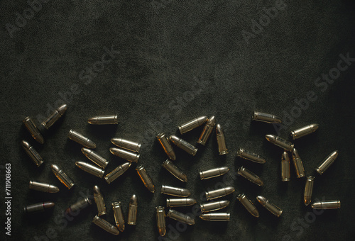 bullets for a combat pistol 9 mm gold color lies on a dark green or khaki background top view close-up