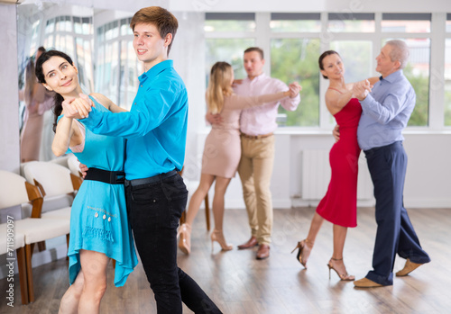 Woman paired with male partner dance samba in class with students