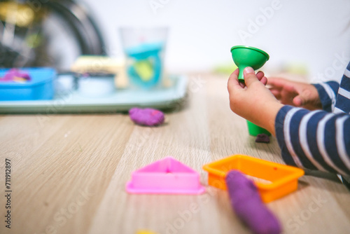 Manos de niña de  2 años jugando con plastilina casera y moldes. Jugar con la plastifica en casa, juguetes educativos para niños Montessori. Juegos creativos para niños pequeños.  photo