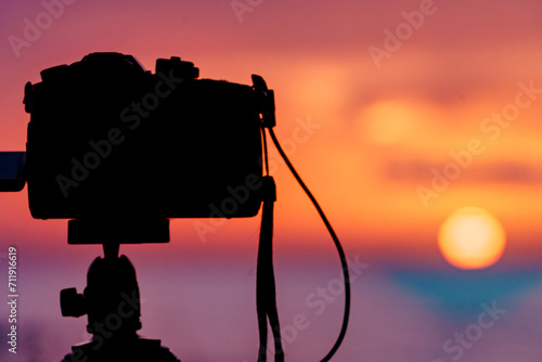 Camera taking photos of sunrise over sea