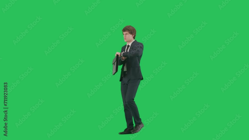 Portrait of male model in suit on chroma key green screen background. Side view, friendly businessman in suit walking checks watch starts running Portrait of male model in suit on chroma key green screen background. Side view, friendly businessman in suit walking checks watch starts running