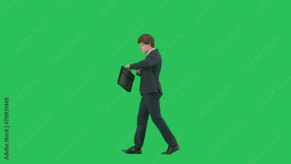 Profile view of male model in suit isolated on chroma key green screen background. Positive young businessman in blue suit walking starts running. Profile view of male model in suit isolated on chroma key green screen background. Positive young businessman in blue suit walking starts running.