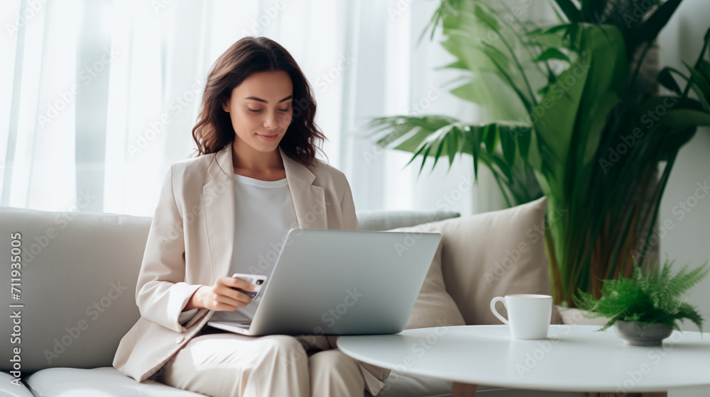 Businesswoman holding a credit card in her hand while using laptop computer. A professional woman working remotely at home and uses internet banking, e-commerce, online shopping, spending money Businesswoman holding a credit card in her hand while using laptop computer. A professional woman working remotely at home and uses internet banking, e-commerce, online shopping, spending money