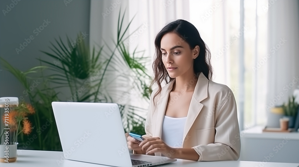 Businesswoman holding a credit card in her hand while using laptop computer. A professional woman working remotely at home and uses internet banking, e-commerce, online shopping, spending money Businesswoman holding a credit card in her hand while using laptop computer. A professional woman working remotely at home and uses internet banking, e-commerce, online shopping, spending money
