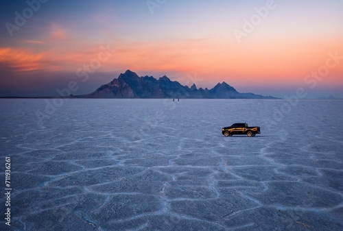 Car riding  driving on salt flats at sunset colorful sky.  Road trip to Utah. Bonneville Salt Flats near Salt Lake City. Utah. USA