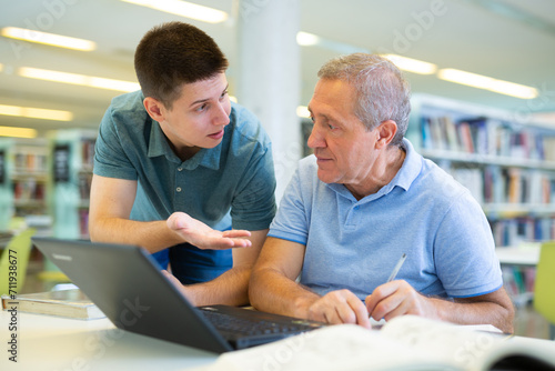 Focused male coworkers discussing remote job and searching in Internet in the library © JackF